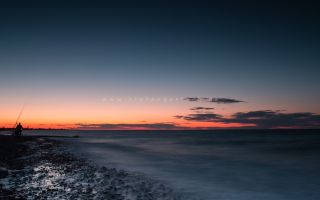 Sonnenuntergang im Sommer an der Ostsee mit Angler